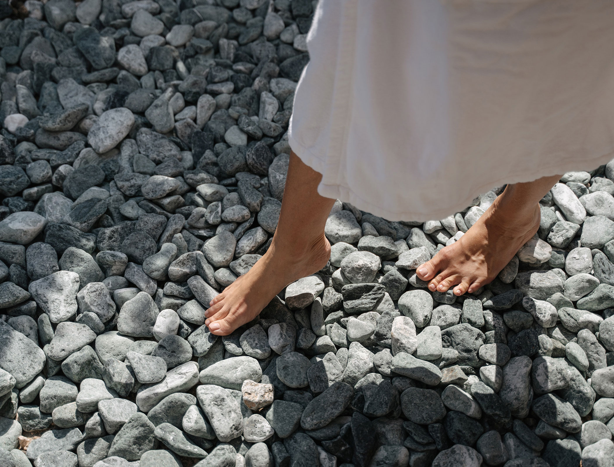 Woman walks barefoot over stones