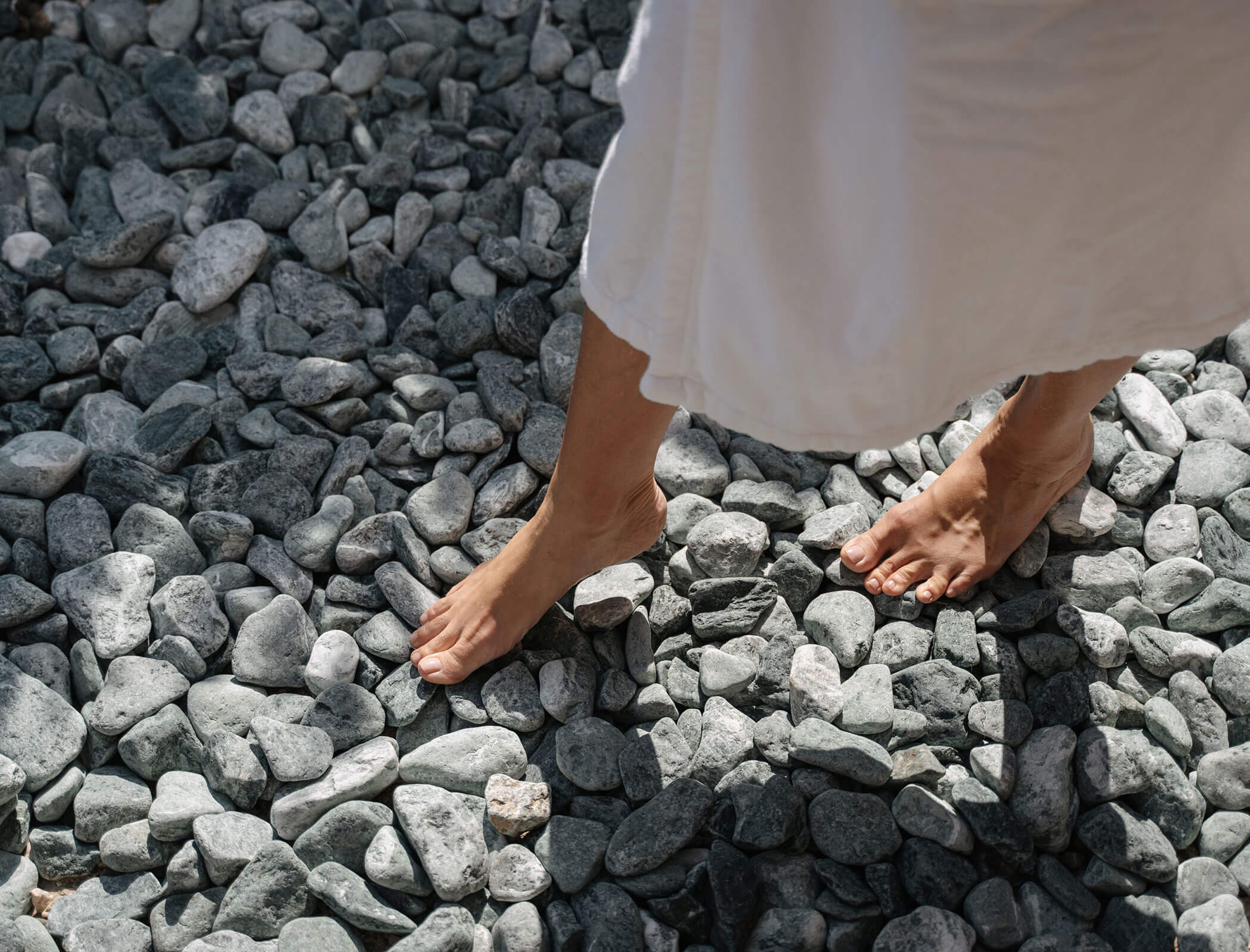 Woman walking barefoot on stones
