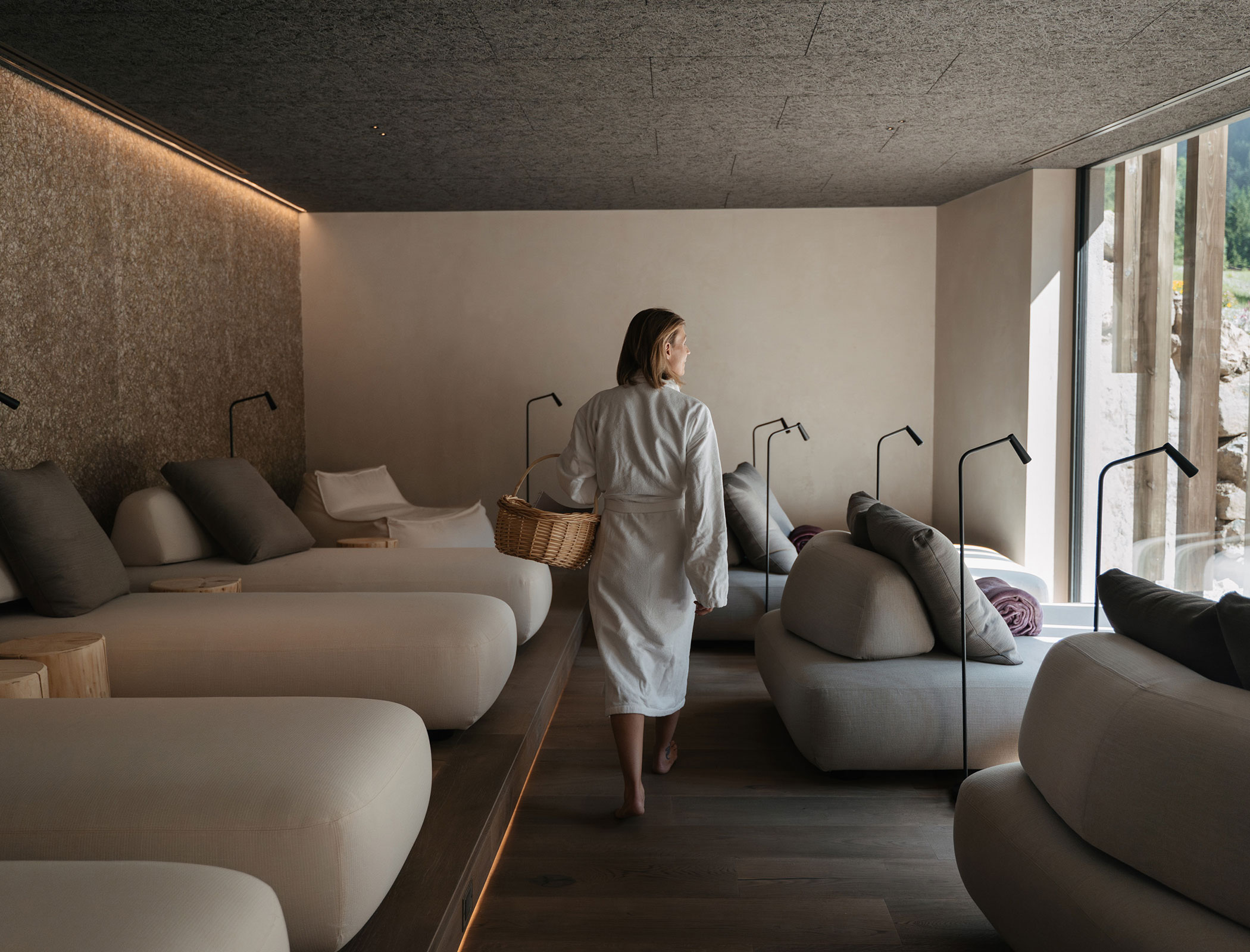 Woman in bathrobe with basket walks through relaxation room