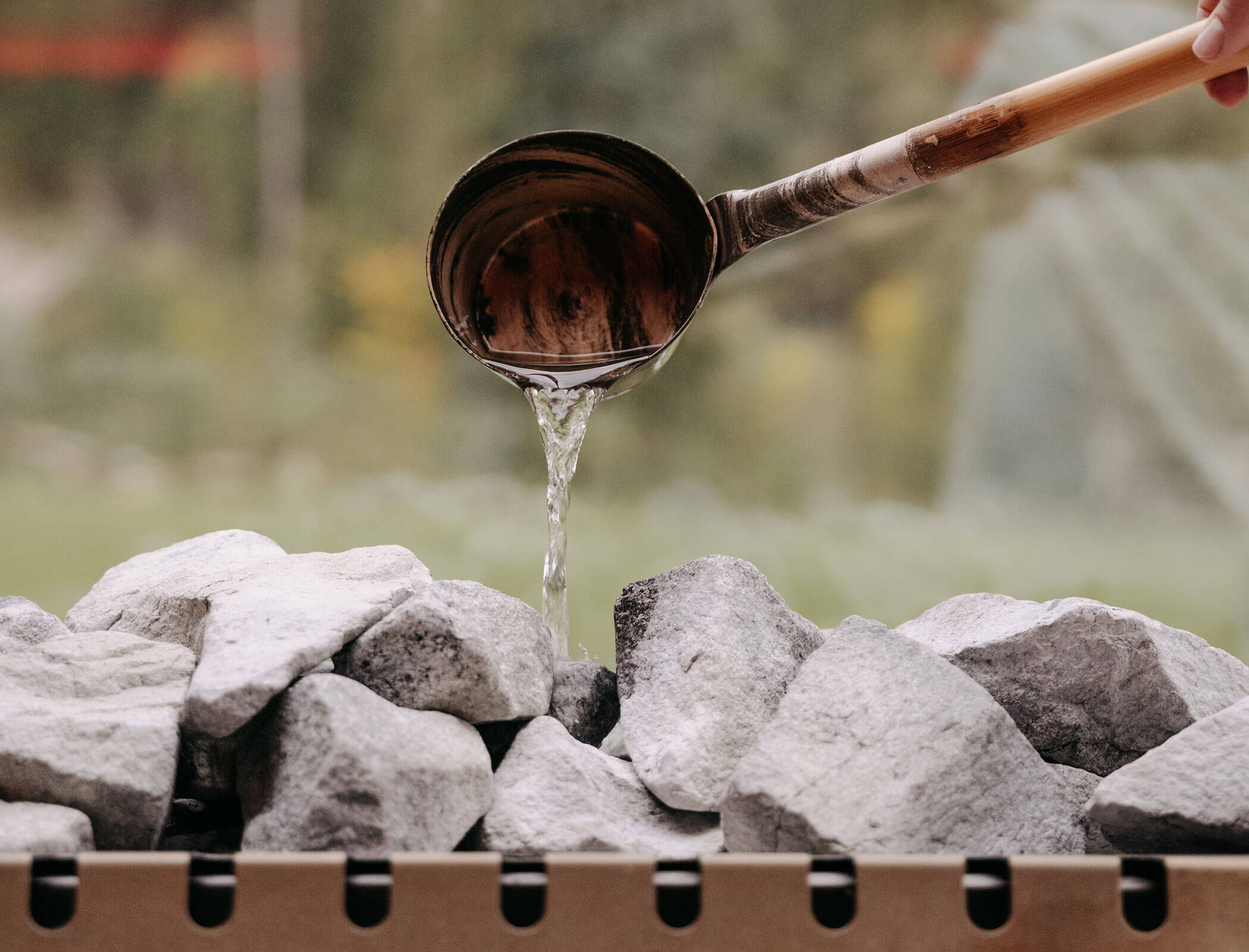 Una mestola d'acqua viene versata sulle pietre calde della sauna - Bad Ratzes
