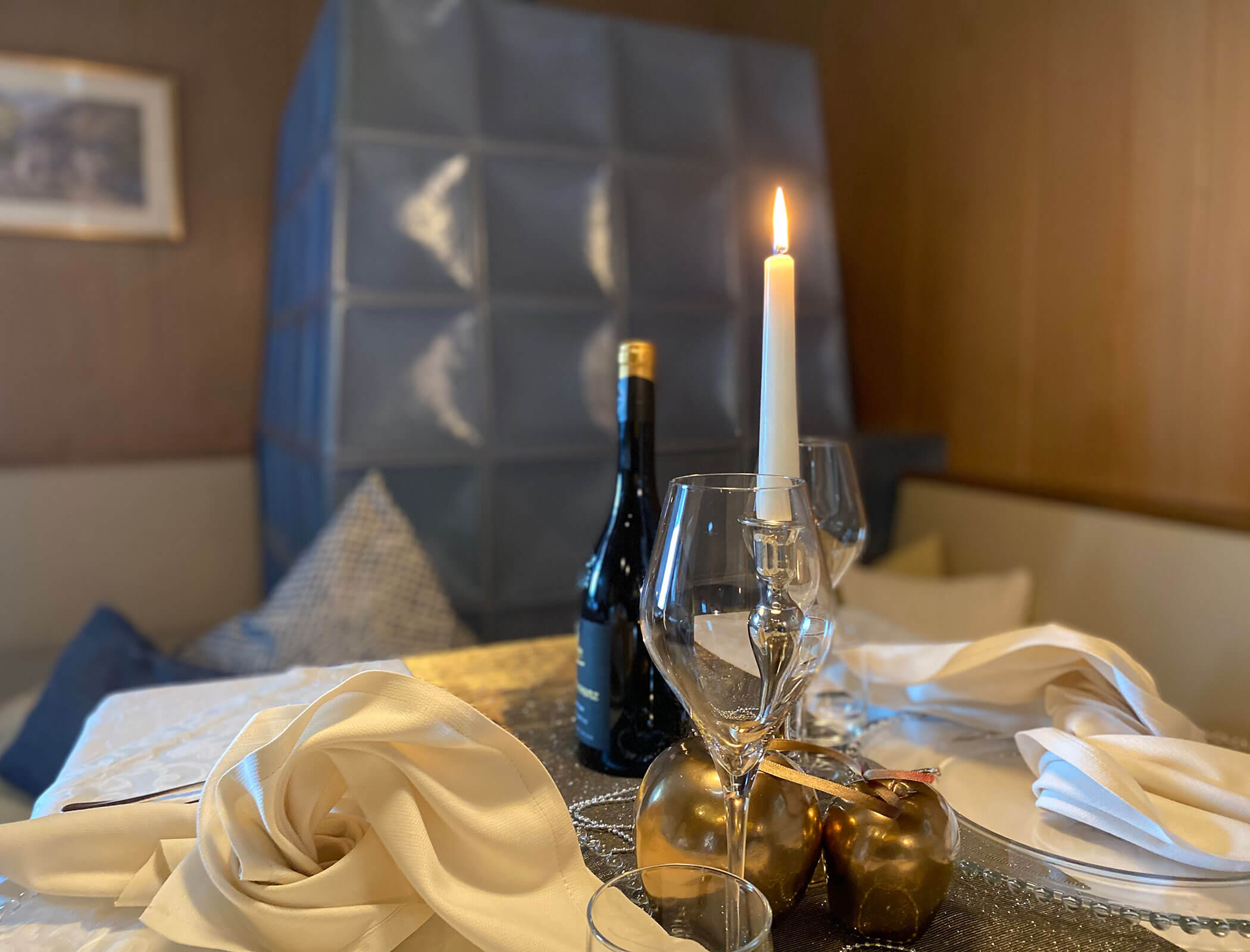 Tavolo apparecchiato con candela accesa e decorazioni dorate - Bad Ratzes
