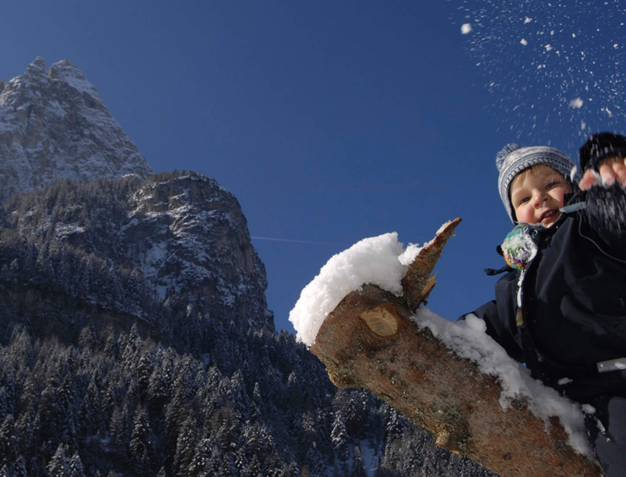 Un bambino gioca con la neve - sullo sfondo le montagne innevate - Bad Ratzes